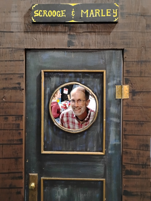Gary Fisk looking through a hole in a door for the community theater play.
